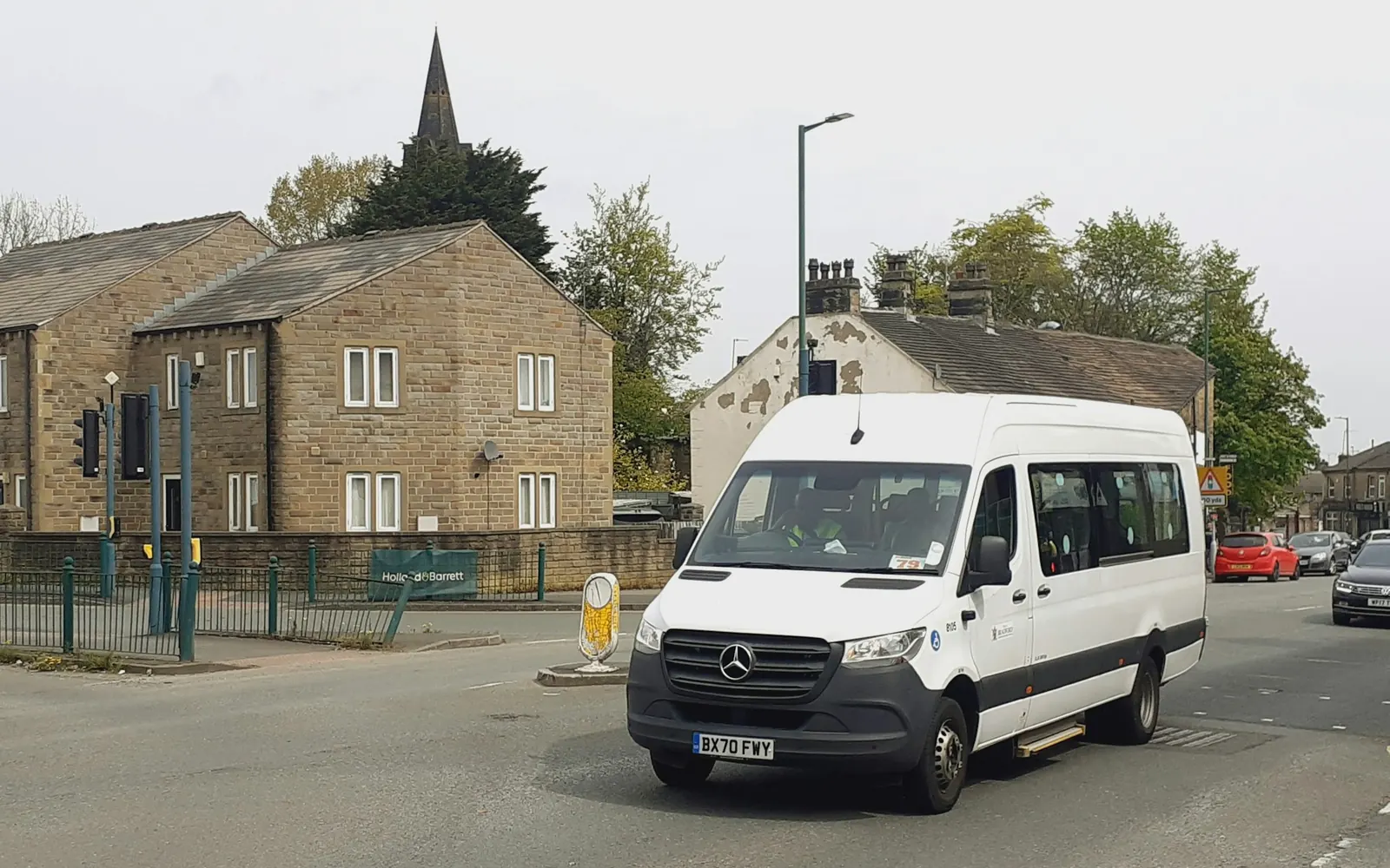 Minibus blanc aménagé pour le transport de personnes à mobilité réduite dans une rue de village