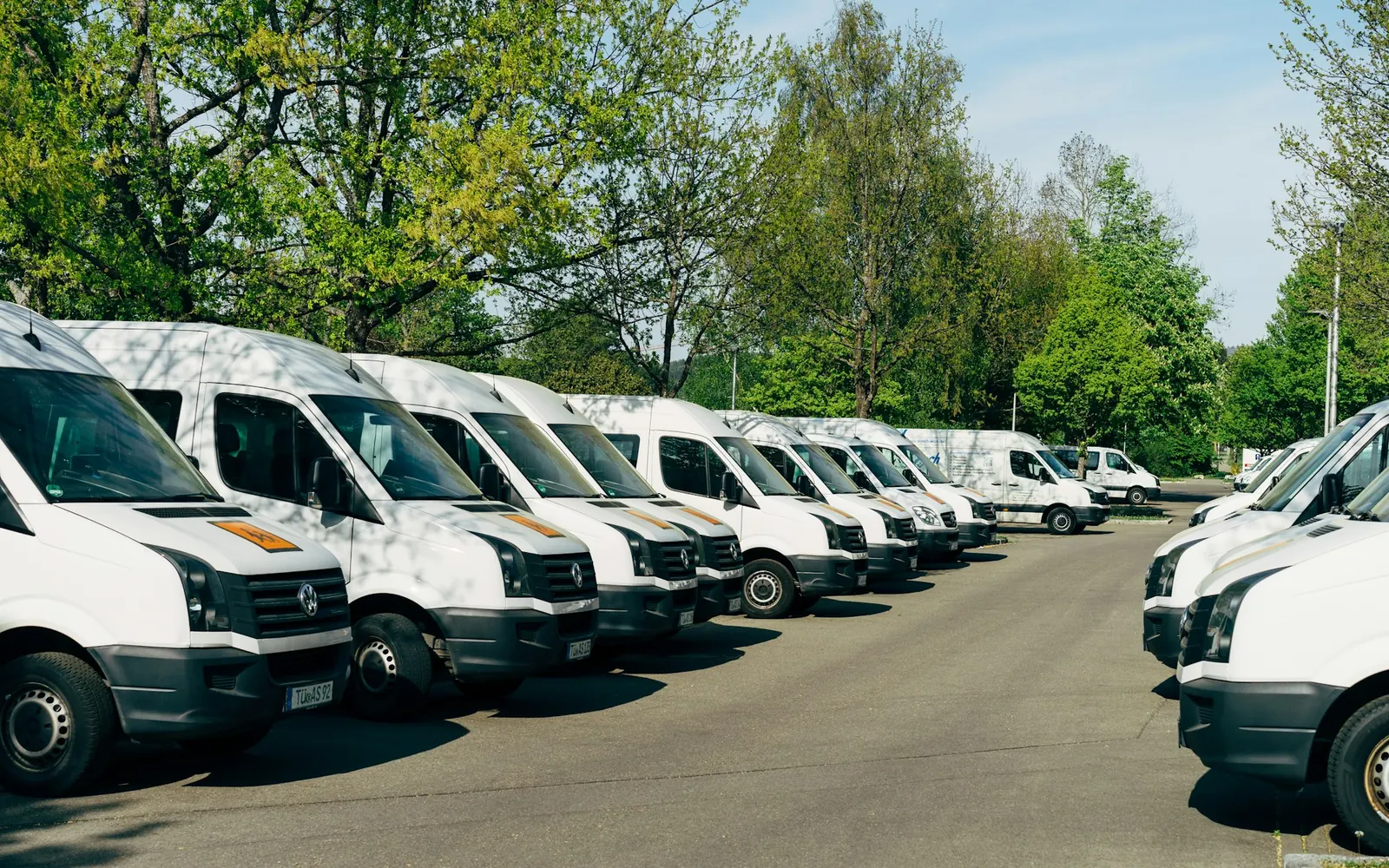 Rangée de vans blancs utilisés par une entreprise de transport de personnes pour plusieurs métiers
