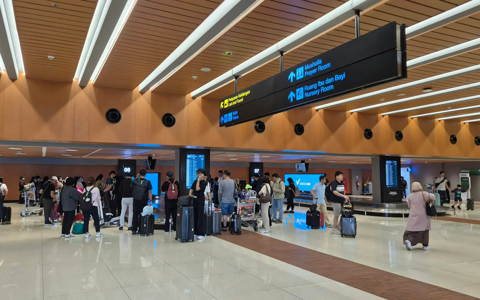Hall des arrivées d’un aéroport avec voyageurs et panneaux, lieu d’accueil d’un transfert aéroport