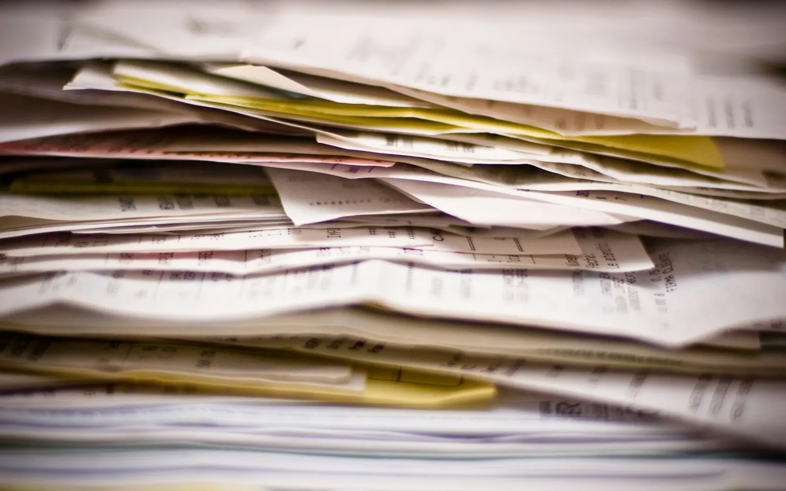 Pile de papiers sur un bureau, bons de course et planning papier d’une entreprise de transport