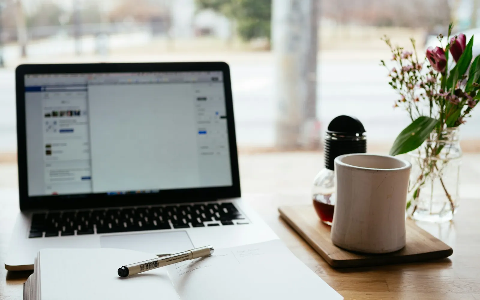 Ordinateur portable ouvert et carnet sur un bureau, pour comparer le prix des formules du logiciel de transport