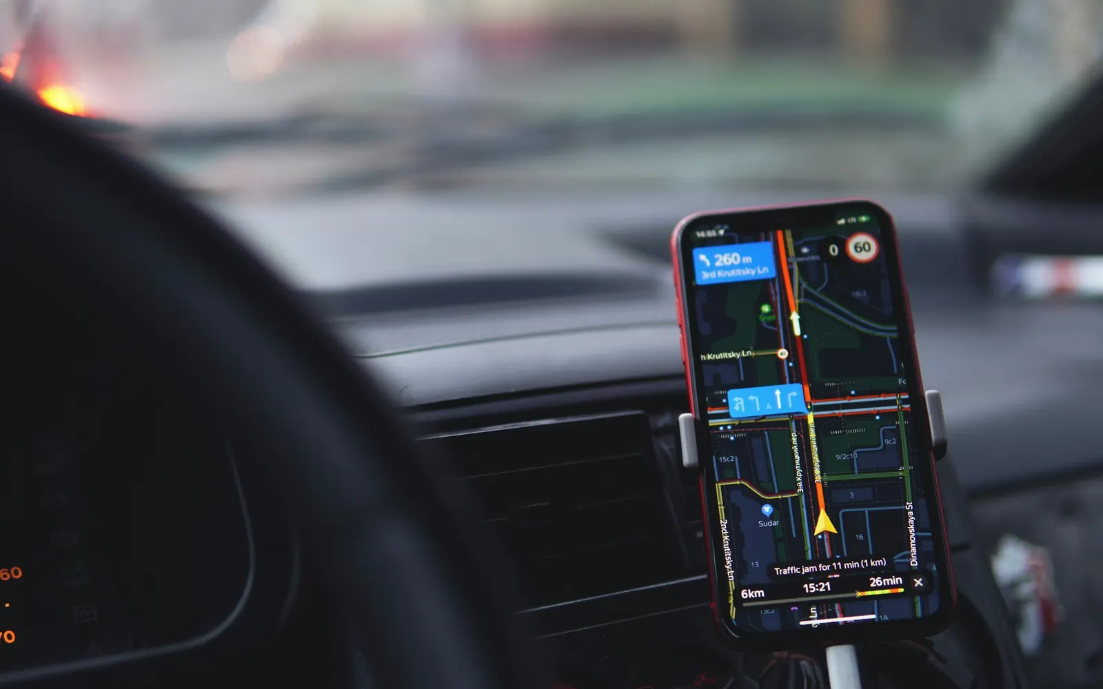 Smartphone fixé sur un support dans une voiture, affichant une carte de navigation pendant une mission