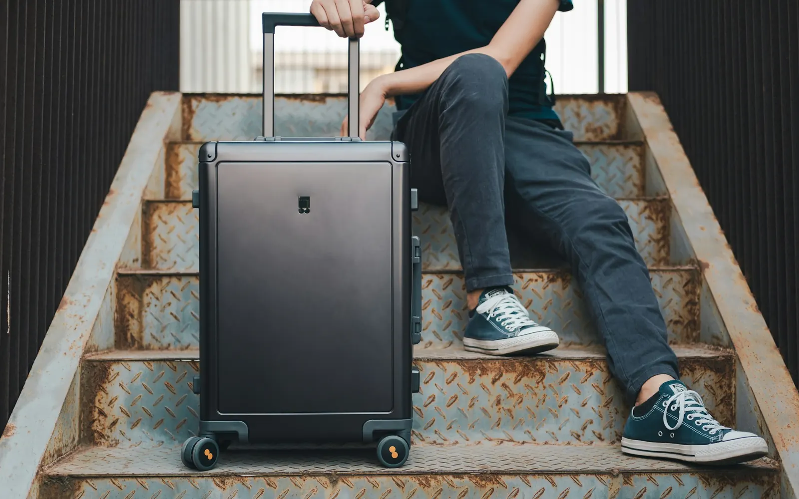 Voyageuse assise avec sa valise cabine, qui réserve son transfert VTC depuis son téléphone